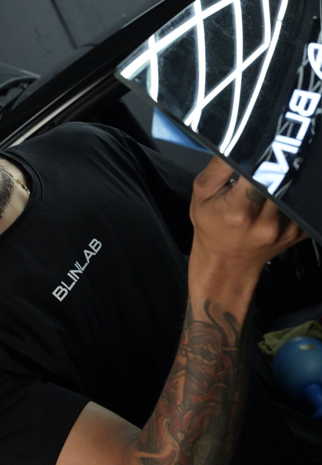 Técnico de Blinlab con camiseta de la marca instalando película en la ventana de un carro